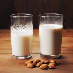 A humorous side-by-side comparison of a glass of cow's milk and a glass of almond milk, with quirky digestive-related symbols surrounding each glass, representing the central question of the blog post.